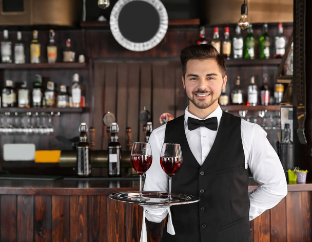Giovane cameriere maschile con bicchieri di vino nel ristorante
 - Foto, immagini