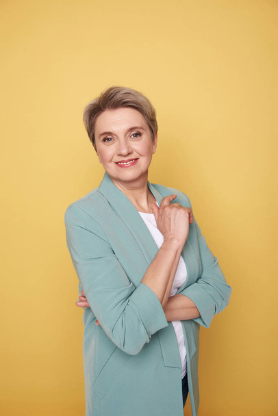 Cheerful mother posing in studio against yellow wall - Foto, imagen