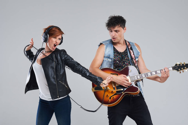 Musical artists sing and play electric guitar. Contemporary cover band. Isolated over grey background. Woman and man with headphones sing loudly - Fotó, kép