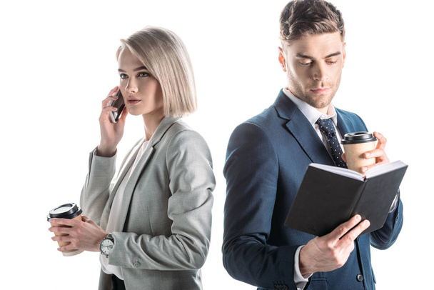attractive businesswoman talking by smartphone near businessman holding notebook isolated on white - Valokuva, kuva