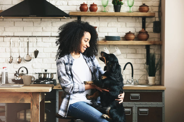 Αφρικανικός-αμερικανική γυναίκα με χαριτωμένο αστείο σκύλο στην κουζίνα - Φωτογραφία, εικόνα