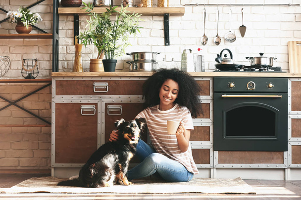 African-American woman with cute funny dog drinking coffee in kitchen - Foto, Imagen
