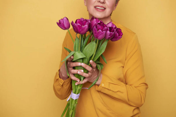 Cropped photo of Caucasian woman with cute bouquet of tulips in arms - Foto, imagen