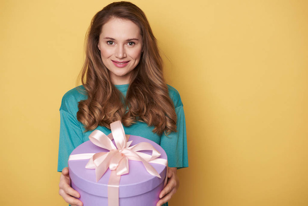 Half length of smiling girl holding a present in arms indoors - Foto, Imagem