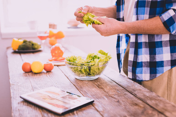 inspirierter Mann bereitet ein Gericht mit Salat zu - Foto, Bild