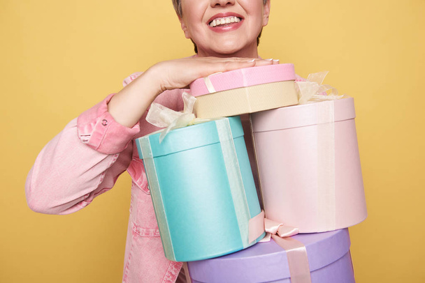 Cropped photo of happy Caucasian mother holding presents on yellow background - Photo, image