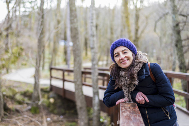 Elölnézet hátizsák áll, közel a régi footbridge mosolygó gyönyörű lány portréja - Fotó, kép