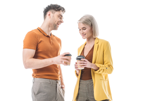 vrolijke jonge man en vrouw houden koffie kopjes en praten geïsoleerd op wit - Foto, afbeelding