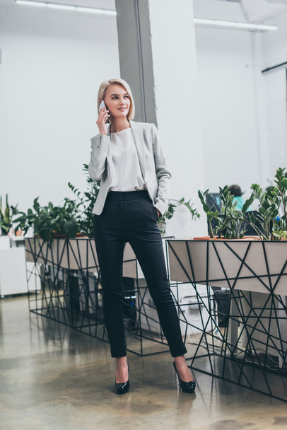 beautiful blonde businesswoman talking on smartphone in office - Photo, Image