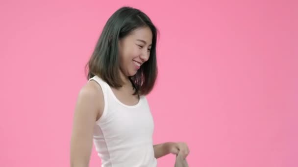 Young beautiful fashionable Asian woman wearing casual clothes over pink background studio shot. Happy smiling adorable glad woman rejoices success. - Video