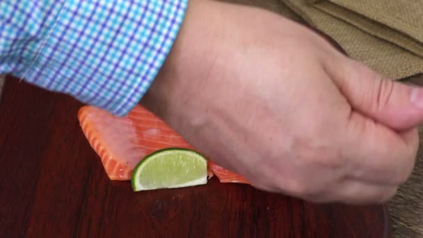 Чоловік кладе перець навколо шматочків лосося на дерев'яний подрібнювач
 - Кадри, відео