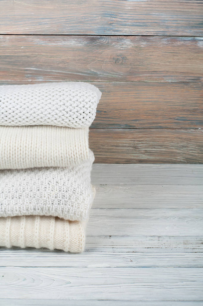 Knitted wool sweaters. Pile of knitted winter clothes on wooden background, sweaters, knitwear, space for text - Foto, Imagem