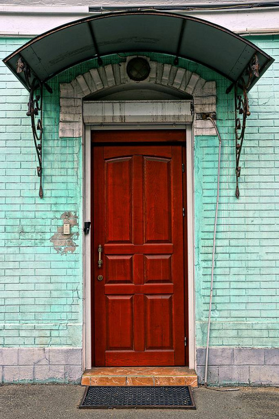 Red entrance wooden door on the facade of a brick building - Фото, изображение