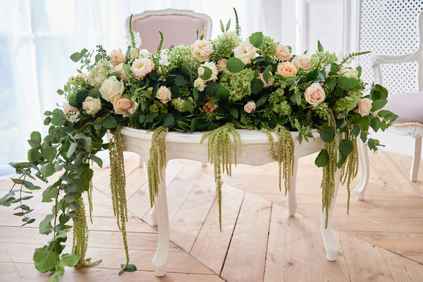 Luxury floral arrangement of pink and beige roses, freesia, hydrangea and amaranth on white wood table, copy space.  Flowers composition for wedding presidium, beautiful decorations - Photo, image