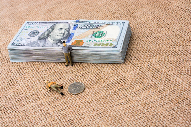 Figuras masculinas al lado del paquete de billetes en dólares
  - Foto, Imagen