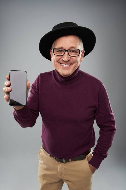 Happy man in black hat showing the screen of modern gadget - Fotoğraf, Görsel