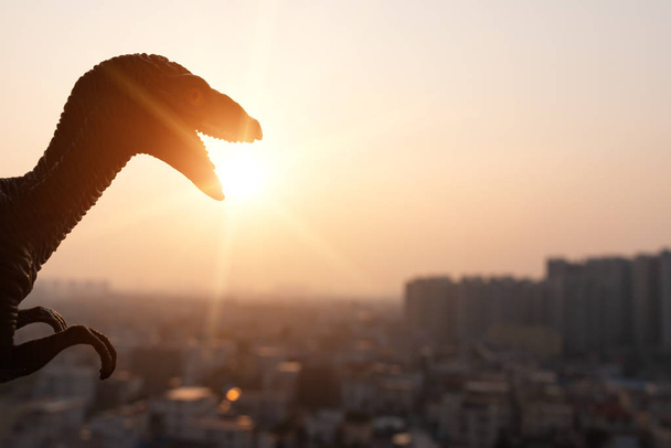 silhouette of deinonychus and buildings in sunset time - Photo, Image