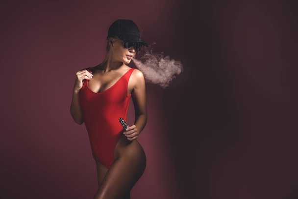 Young sexy woman is vaping. A cloud of vapor. Studio shooting. - Foto, imagen