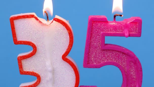 Number thirty five shaped burning candle on blue - Footage, Video