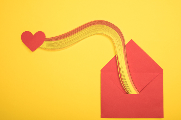 κάτοψη του ανοικτό κόκκινο φάκελο με ουράνιο τόξο και καρδιά συνδεθείτε σε κίτρινο φόντο - Φωτογραφία, εικόνα