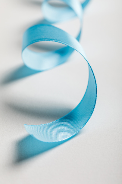 close up of curved blue satin ribbon on grey background - Фото, изображение