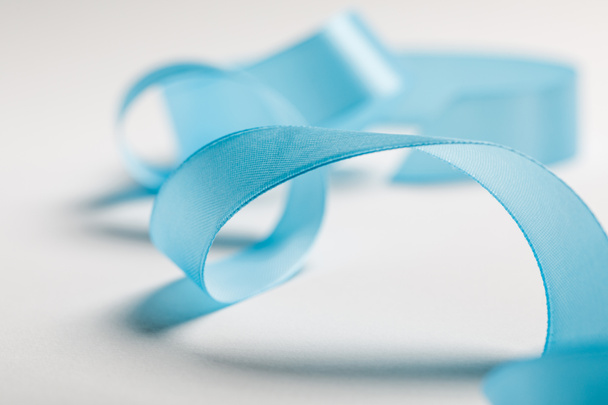 close up of wavy blue satin ribbon on grey background - Foto, afbeelding