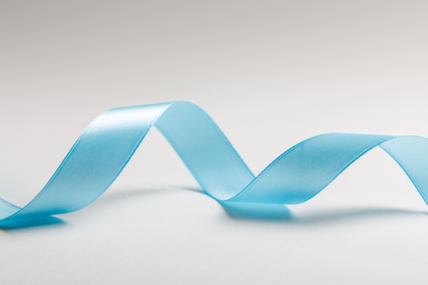 close up of wavy blue silk ribbon on grey background - Zdjęcie, obraz
