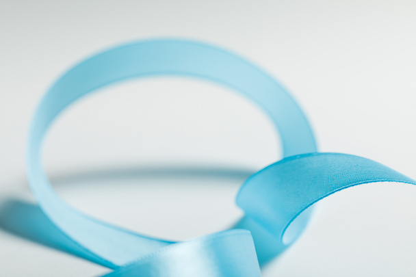 close up of curved blue satin ribbon on grey background - Foto, imagen