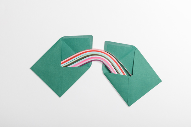 top view of green envelopes with multicolored rainbow on grey background - Foto, Imagen