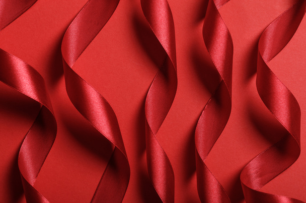 close up of wavy silk red ribbons on red background - Foto, Bild