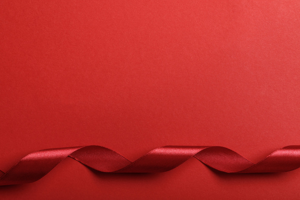 top view of curved silk red ribbon on red background  - Foto, Imagen