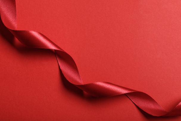 top view of curved silk red ribbon on red background with copy space - Fotoğraf, Görsel