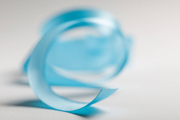 selective focus of curved blue satin ribbon on grey background - Foto, Bild