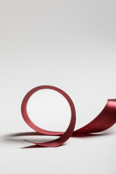 satin curved burgundy ribbon on grey background - Photo, Image