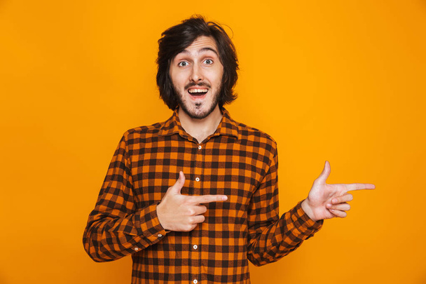 Handsome young happy man isolated over yellow wall background pointing. - Φωτογραφία, εικόνα