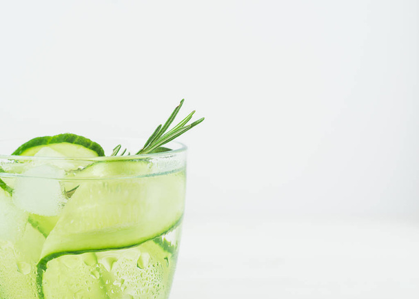 Verse komkommer drankje takje rozemarijn in een glas goblet op witte achtergrond. Zomer verfrissende detox. Selectieve aandacht. - Foto, afbeelding