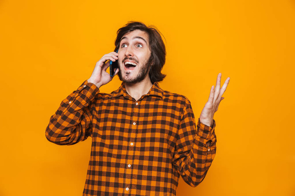 Photo of brunette man wearing plaid shirt using and talking on m - Foto, immagini