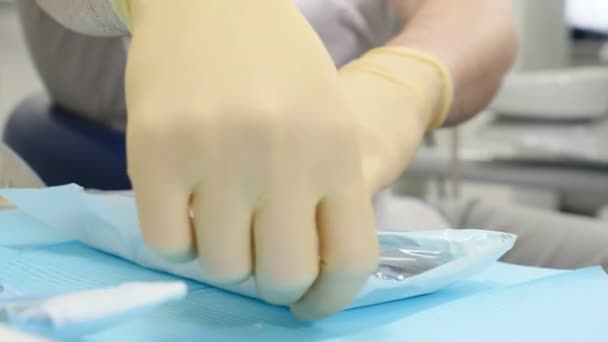 Male dentist opens aseptic tools. dentist unpacks sterile dental instruments. 4k - Filmmaterial, Video