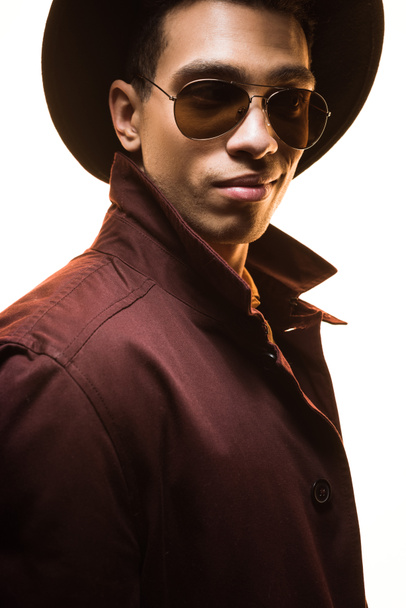 fashionable mixed race man in sunglasses and hat posing isolated on white - Foto, afbeelding