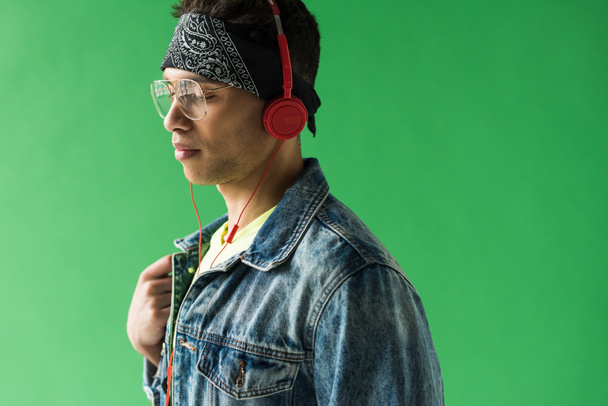 handsome mixed race man in headphones listening music on green screen with copy space - Foto, afbeelding