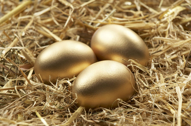 THREE GOLD EGGS IN NEST OF STRAW - Photo, Image
