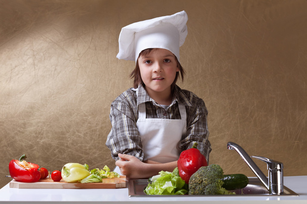 Little boy with chef hat washing vegetables - Фото, зображення