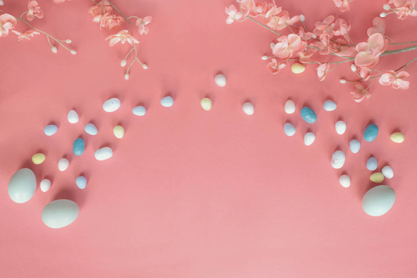 Pastel Easter Eggs Malt Candy and Flowers over a Coral Colored B - Φωτογραφία, εικόνα
