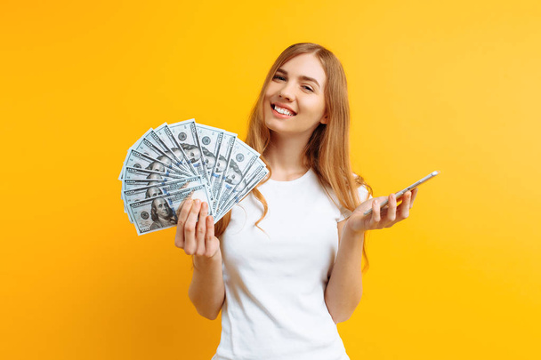 Portrait of an excited woman showing money bills and holding mob - Fotografie, Obrázek