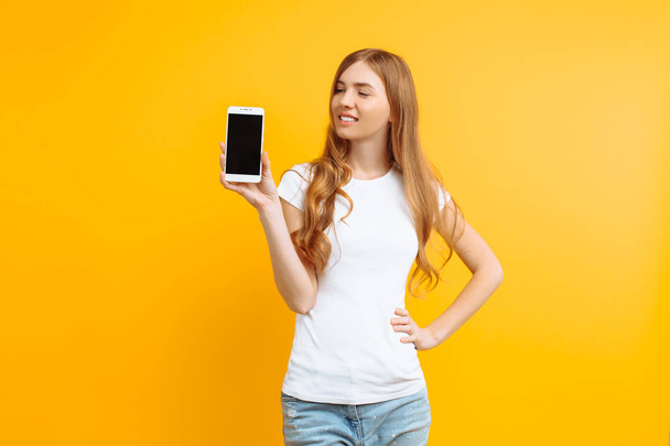 Πορτρέτο του μια όμορφη κοπέλα, που δείχνει μια κενή οθόνη τηλέφωνο σε ένα - Φωτογραφία, εικόνα