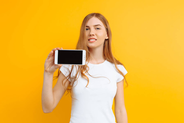 Retrato de una hermosa chica, mostrando un teléfono de pantalla en blanco en un
 - Foto, imagen