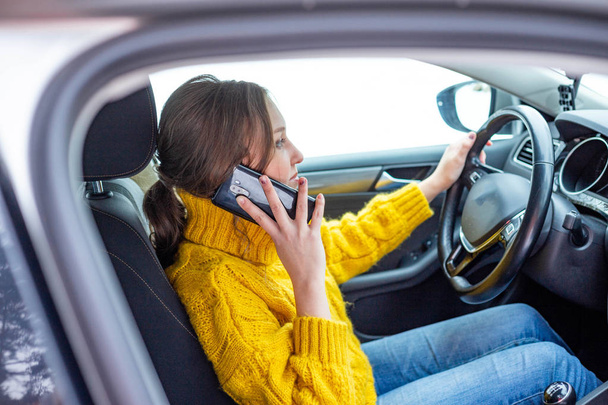 Woman is talking on her phone while driving a car - Photo, image