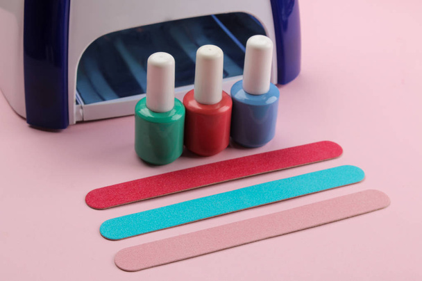 Manicure. UV-lamp en nagelvijltjes en nagel schoensmeer op een zachte roze achtergrond. Manicure accessoires en gereedschappen voor nagels. - Foto, afbeelding
