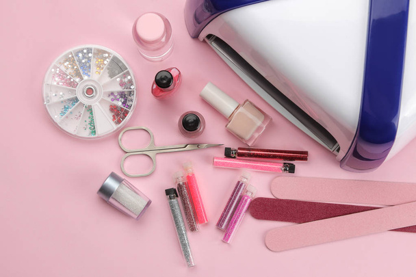 Maniküre. Nagellack, UV-Lampe und diverses Zubehör und Werkzeug für die Maniküre auf trendigem rosa Hintergrund. Ansicht von oben - Foto, Bild
