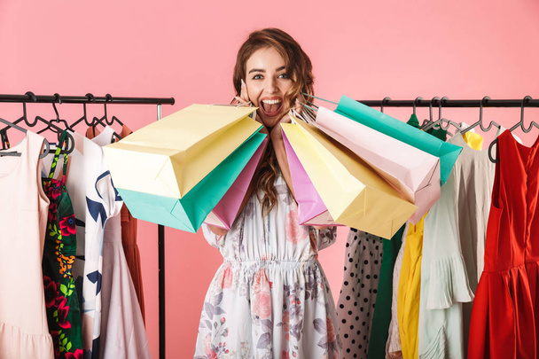 Photo of happy girl standing in store near clothes rack and hold - Foto, imagen